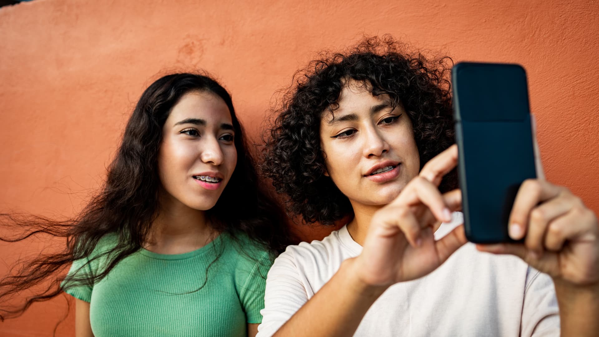 Dos chicas jóvenes utilizando su teléfono móvil.