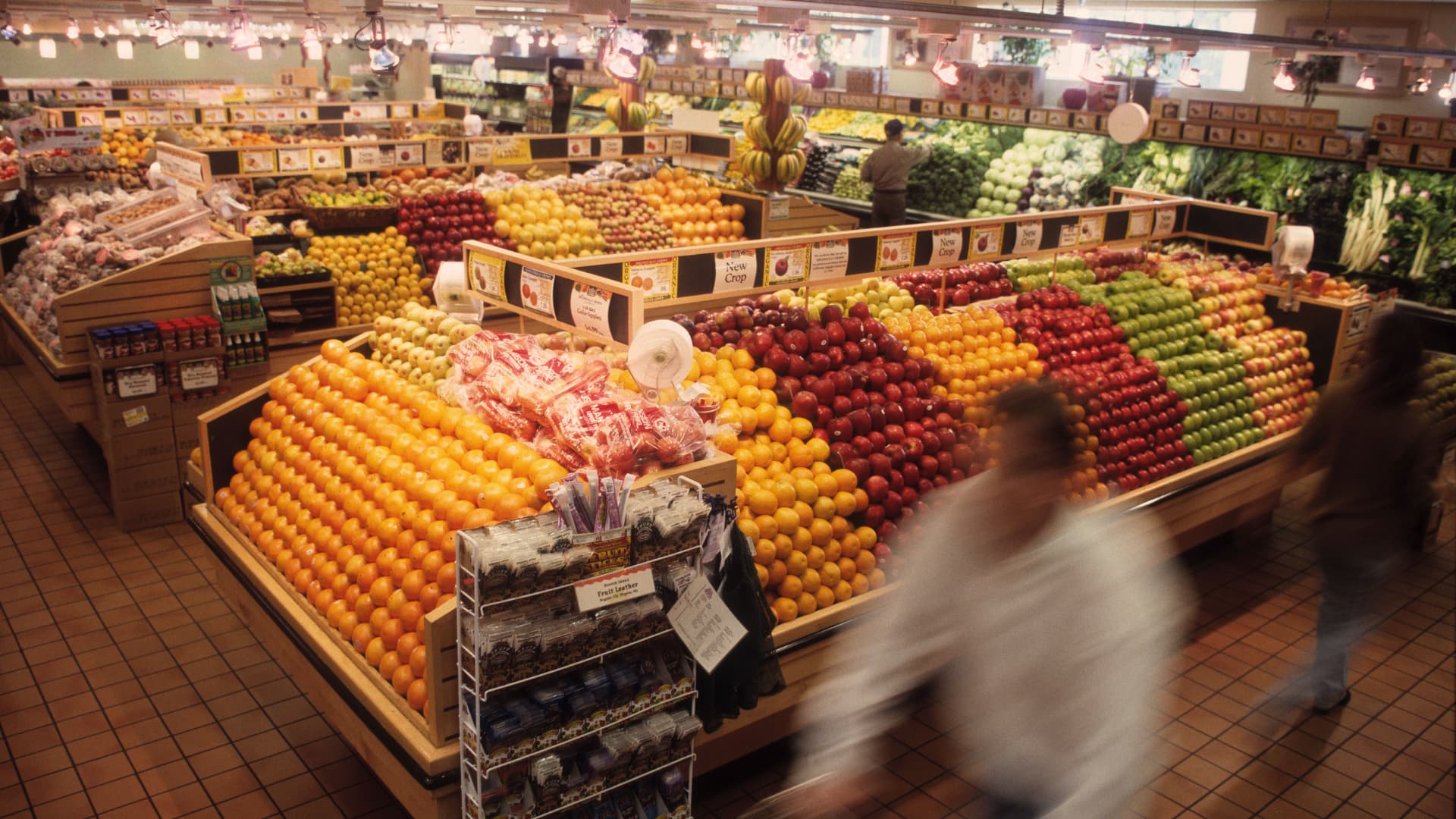 Supermercado, sección de fruta y verdura con gente comprando.