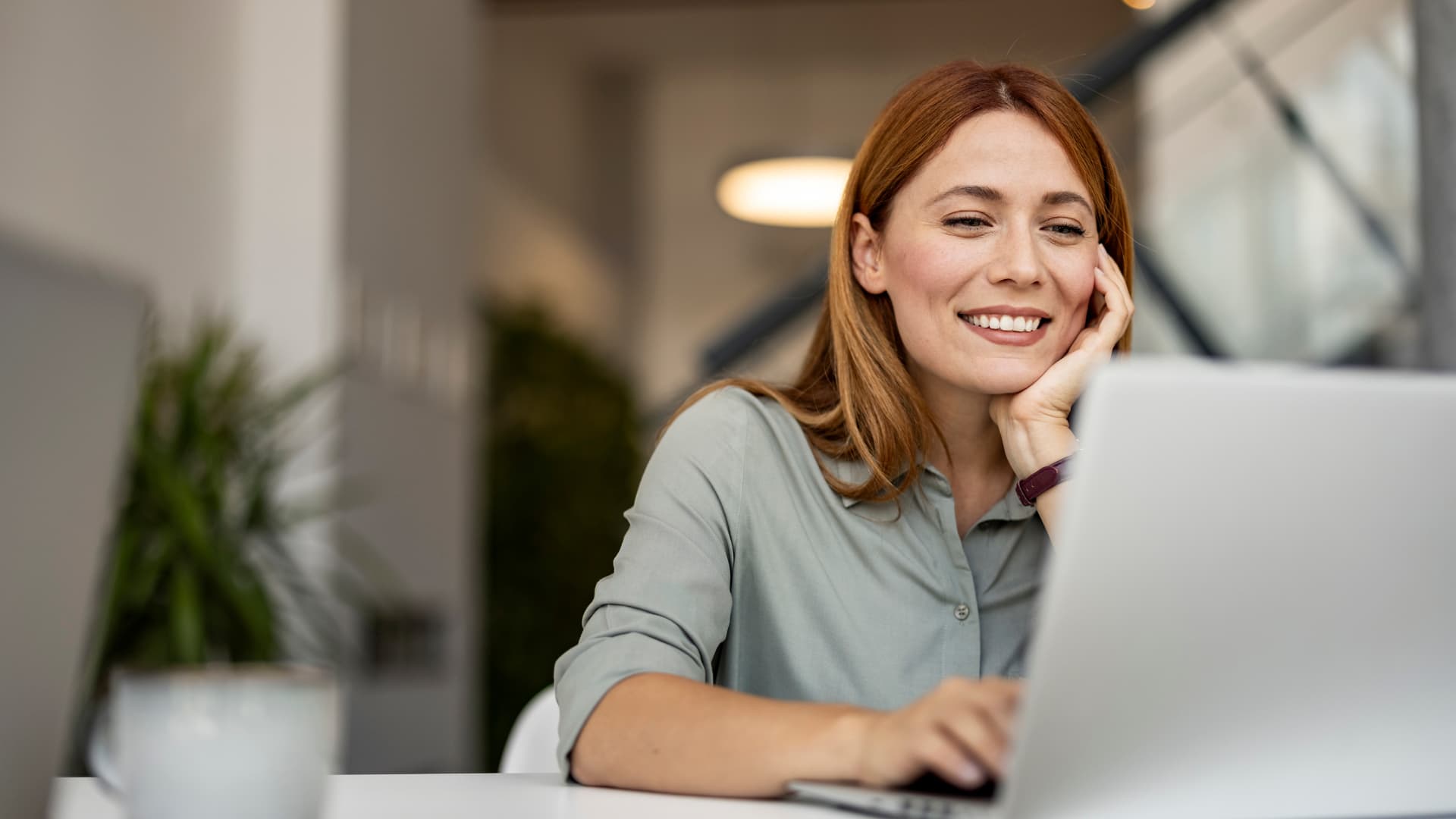 Mujer contenta teletrabajando desde su casa.