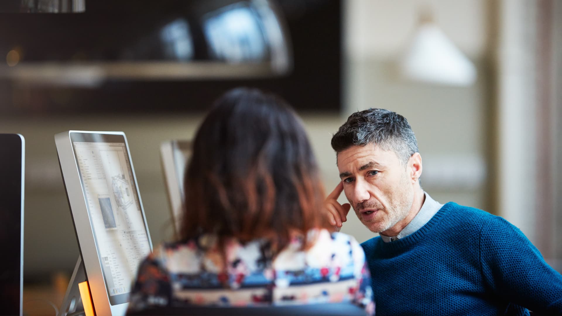 Hombre y mujer en su puesto de trabajo de tecnología e informática hablando.