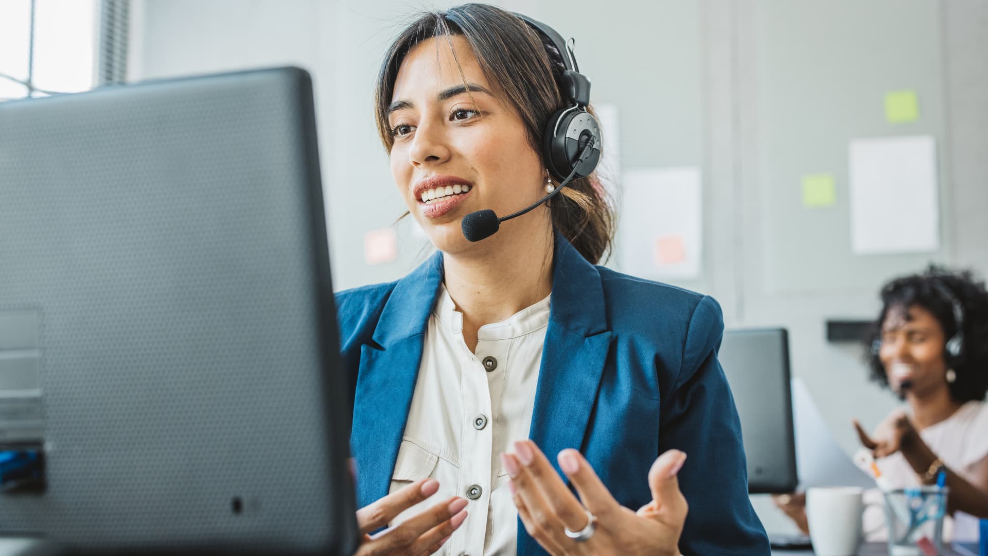Mujer agente atendiendo una llamada en su puesto de trabajo. Contact center y atención al cliente.