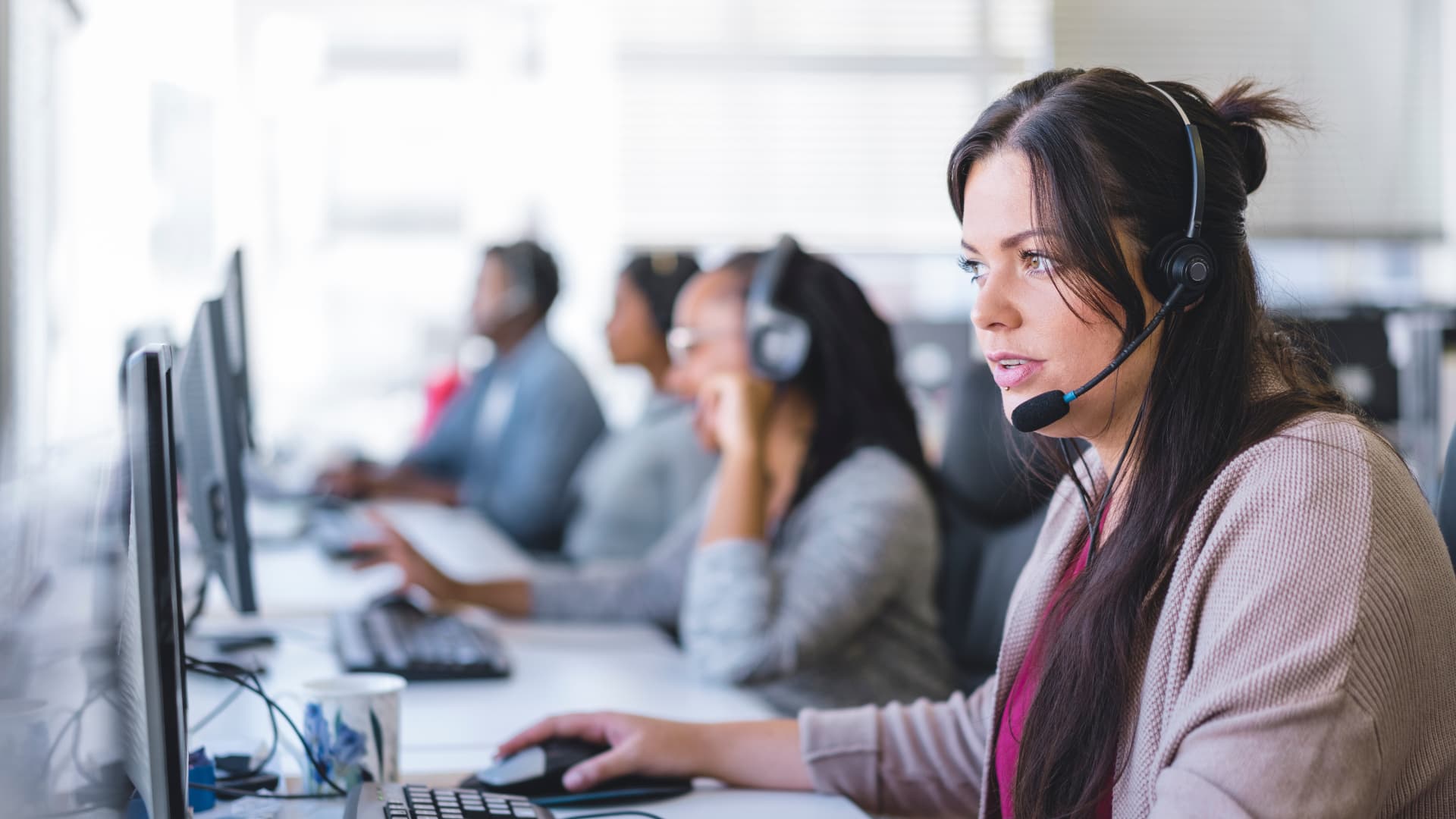 Agentes en un centro de contact center atendiendo llamadas con auriculares para mejorar la contactabilidad.