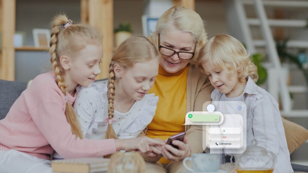 3 hermanos niños de pelo rubio junto a su abuela mirando el smartphone utilizando WhatsApp en casa.