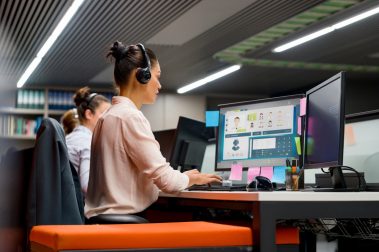 Mujer en su puesto de trabajo de atención al cliente mejorando la experiencia del usuario gracias a la omnicanalidad: teléfono, mensajes, chat.