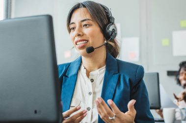 Mujer agente atendiendo una llamada en su puesto de trabajo. Contact center y atención al cliente.